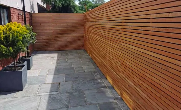 Slate paved garden area next to horizontal wood slat fence