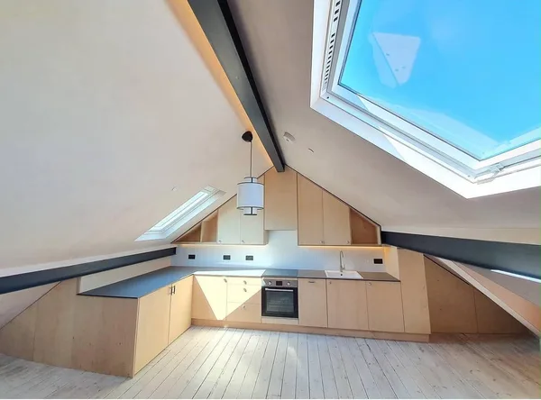 Custom wooden kitchen layout under angled skylight loft roof
