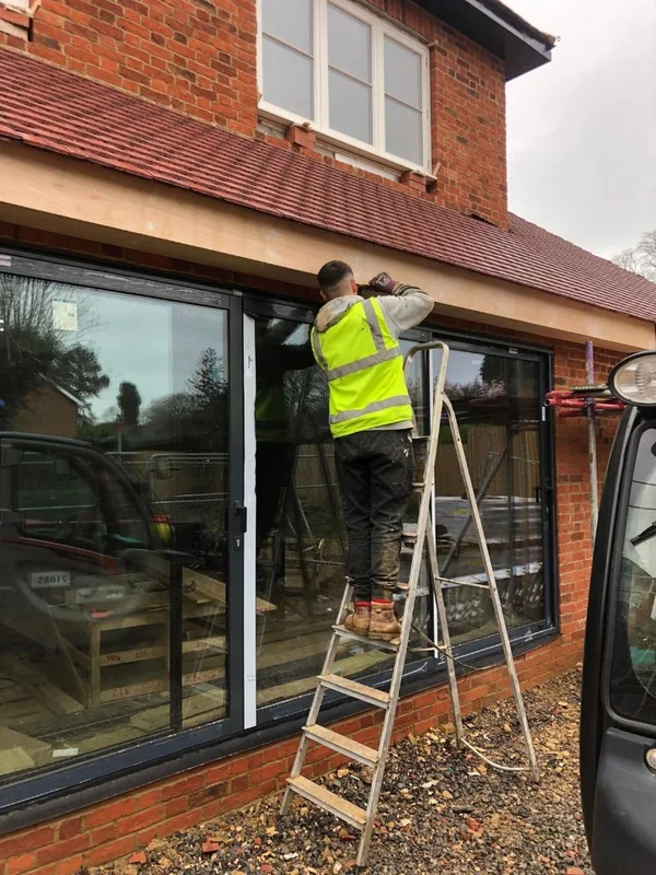 Construction worker installing window frames on ladder